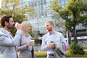 Businesspeople with disposable cups conversing in city