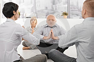 Businesspeople exercising yoga in office