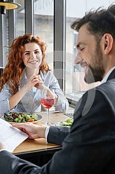 Businesspeople having business lunch at restaurant sitting eating salad drinking wine man reading contract smiling while