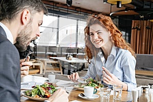 Businesspeople having business lunch at restaurant sitting man eating salad concentrated while woman laughing