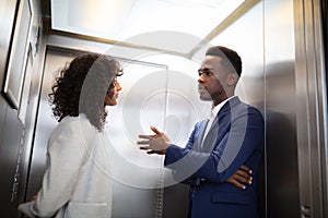 Businesspeople Having Conversation In Elevator