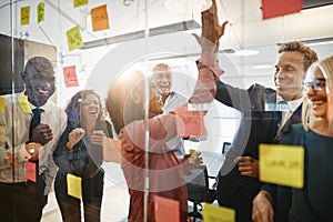 Businesspeople high fiving together with colleagues in an office