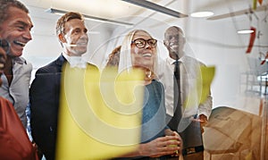 Businesspeople laughing while brainstorming with sticky notes in