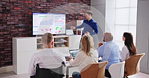 Businesspeople Looking At Businessman Giving Presentation