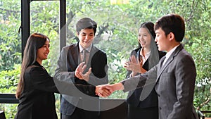 Businesspeople are making confidence in others with handshakes while standing in the meeting room.