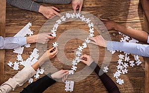 Businesspeople Making Question Mark Sign With Jigsaw Puzzle