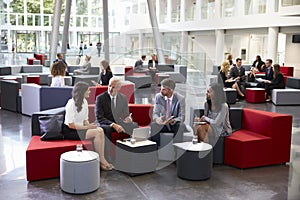 Businesspeople Meeting In Busy Lobby Of Modern Office