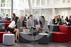 Businesspeople Meeting In Busy Lobby Of Modern Office