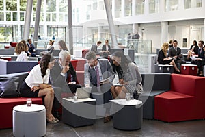 Businesspeople Meeting In Busy Lobby Of Modern Office