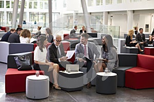 Businesspeople Meeting In Busy Lobby Of Modern Office