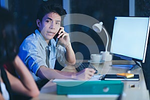 Businesspeople in the office at night working late, coffee and  calling phone working overtime together over a laptop at a desk in