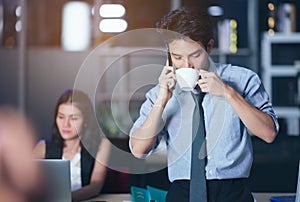 Businesspeople in the office at night working late, coffee and  calling phone working overtime together over a laptop at a desk in