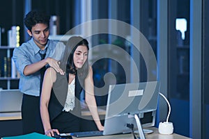 Businesspeople in the office at night working late, Two young businesspeople working overtime together over a laptop at a desk in