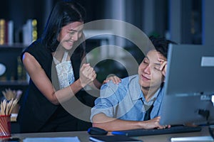 Businesspeople in the office at night working late, Two young businesspeople working overtime together over a laptop at a desk in