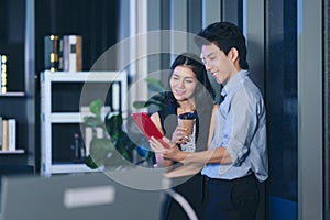 Businesspeople in the office at night working late, Two young businesspeople working overtime together over a laptop at a desk in