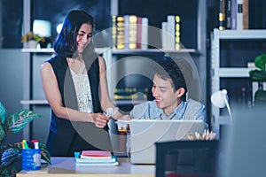 Businesspeople in the office at night working late, Two young businesspeople working overtime together takeout food