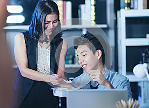 Businesspeople in the office at night working late, Two young businesspeople working overtime together takeout food