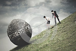 Businesspeople pull a boulder with Persistence text