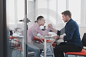 Businesspeople, rivalry and people concept - businesswoman and businessman arm wrestling during corporate meeting in