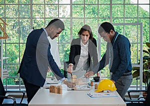 Businesspeople`s multiracial colleagues brainstorm with house models and blueprints at the office. Professional construction team