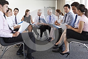 Businesspeople Seated In Circle At Company Seminar