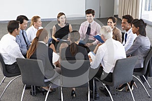 Businesspeople Seated In Circle At Company Seminar