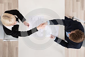 Businesspeople Shaking Hand At Desk