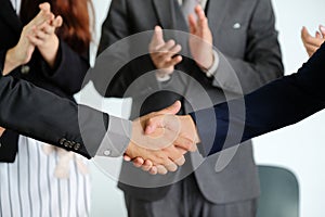 Businesspeople shaking hands against room