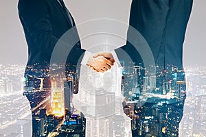 Businesspeople shaking hands on night city background. Teamwork, success and partnership concept. Double exposure