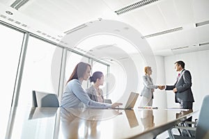 Businesspeople shaking hands in board room