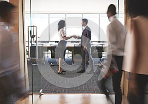 Businesspeople Shaking Hands In Entrance To Boardroom