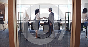 Businesspeople Shaking Hands In Entrance To Boardroom