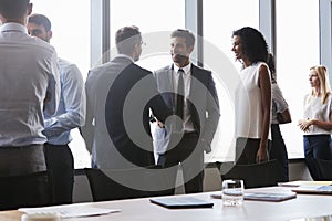 Businesspeople Shaking Hands Before Meeting In Boardroom