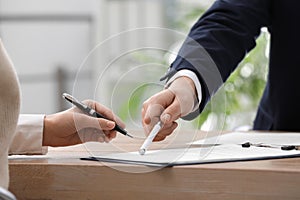 Businesspeople signing contract at table in office, closeup