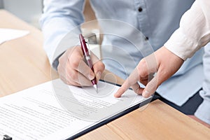 Businesspeople signing contract at table in office, closeup