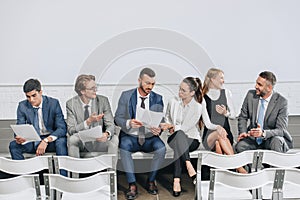 businesspeople sitting with documents on stage and talking