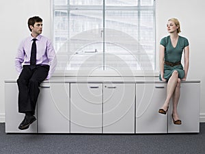 Businesspeople Sitting On Office Cabinets