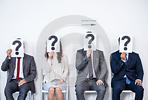 Businesspeople sitting in queue and waiting for interview, holding question marks in office