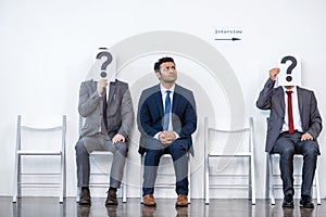 Businesspeople sitting in queue and waiting for interview, holding question marks in office