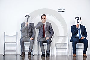 Businesspeople sitting in queue and waiting for interview, holding question marks in office