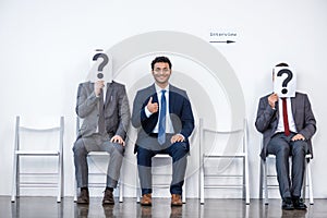 Businesspeople sitting in queue and waiting for interview, holding question marks in office