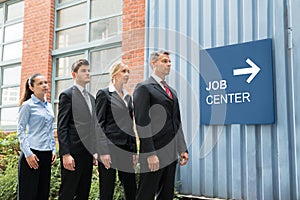Businesspeople Standing Near The Job Center Signboard