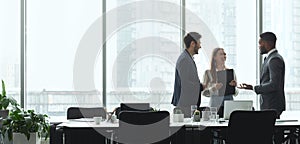 Businesspeople talking in office, standing against window