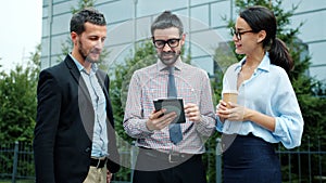 Businesspeople talking using tablet outside near office center discussing business