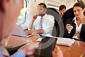 Businesspeople On Train Using Digital Devices