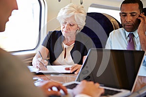 Businesspeople On Train Using Digital Devices