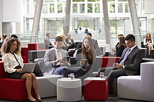 Businesspeople Using Digital Devices In Busy Office Lobby