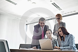 Businesspeople using laptop in conference room