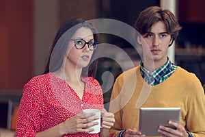 Businesspeople using tablet computer, talking in office.