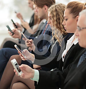 Businesspeople Using Technology In Busy Lobby Area Of Office